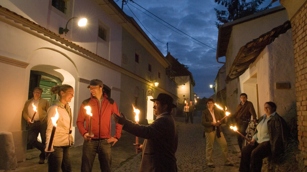 Lange Nacht der Kellergassen: Menschen mit Fackeln in einer Kellergasse